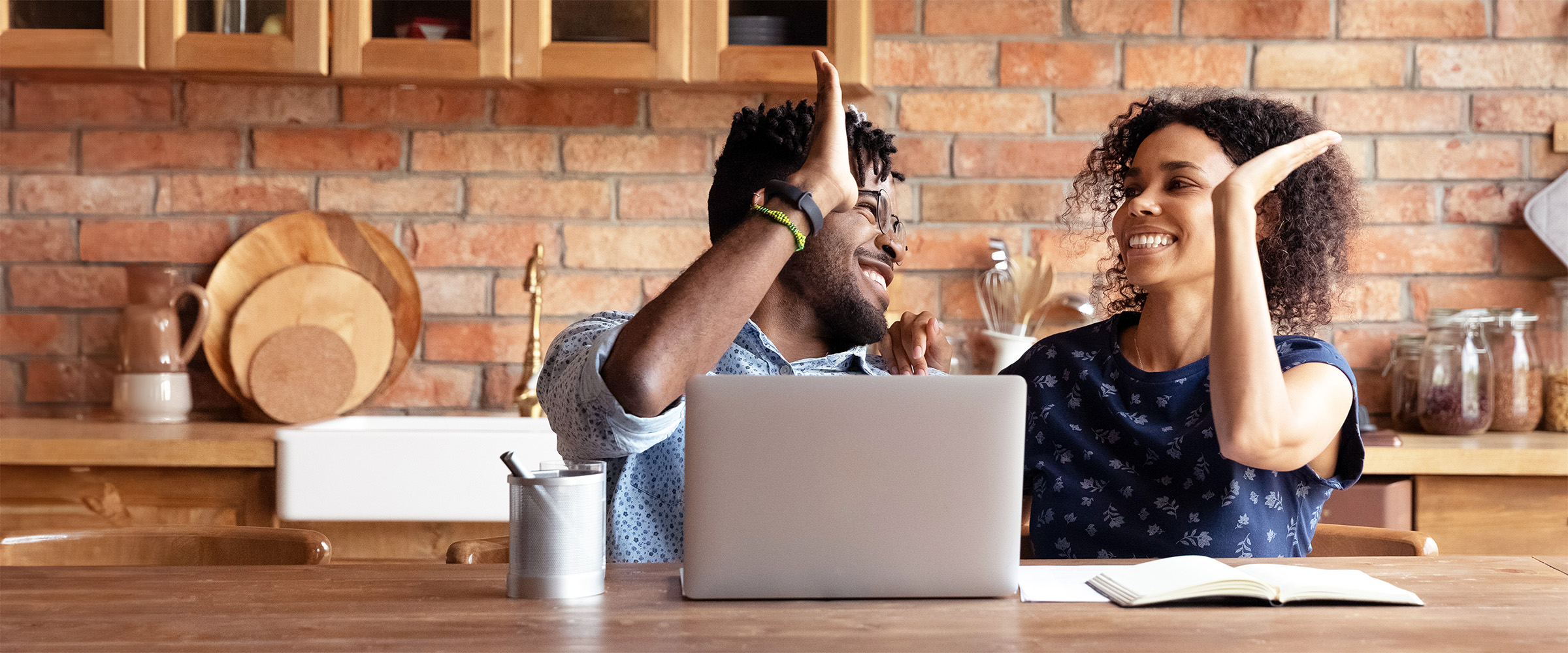 Photo of couple at table with hands raised giving each other high fives.